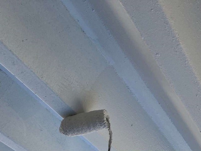 カーポートの折板屋根にガイナを塗装している様子