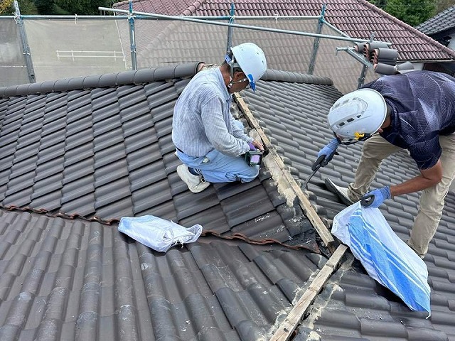 屋根棟瓦取り直し工事の既存棟土台部の漆喰をバールではつっている様子