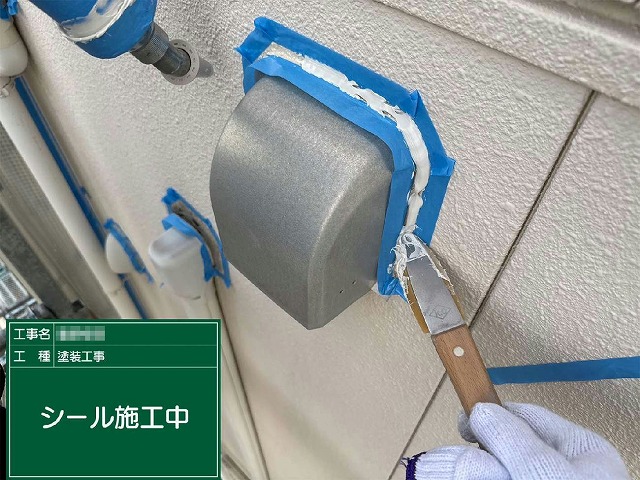コーキング打ち替え工程の換気フードまわりへのヘラ押さえ作業