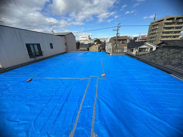 雨漏りをブルーシートで覆ってしのいでいる陸屋根住宅