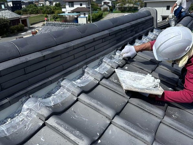 大棟の三日月部に南蛮漆喰を詰めている屋根職人