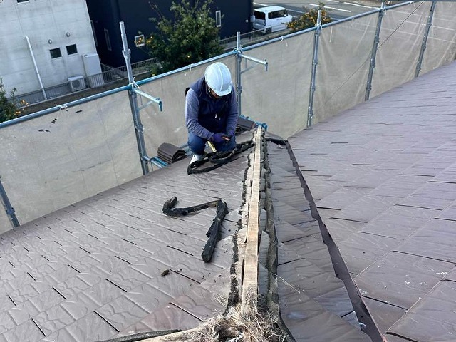 棟部の木下地と防水シーラーを撤去している職人の作業風景