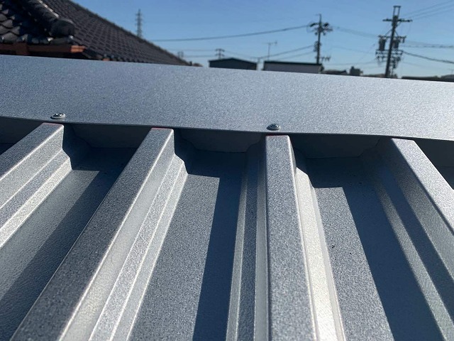 折板屋根カバー工法で棟板金を専用ビスで固定している状況