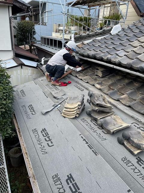 防水シート貼り施工後にマスカー養生を行う屋根職人