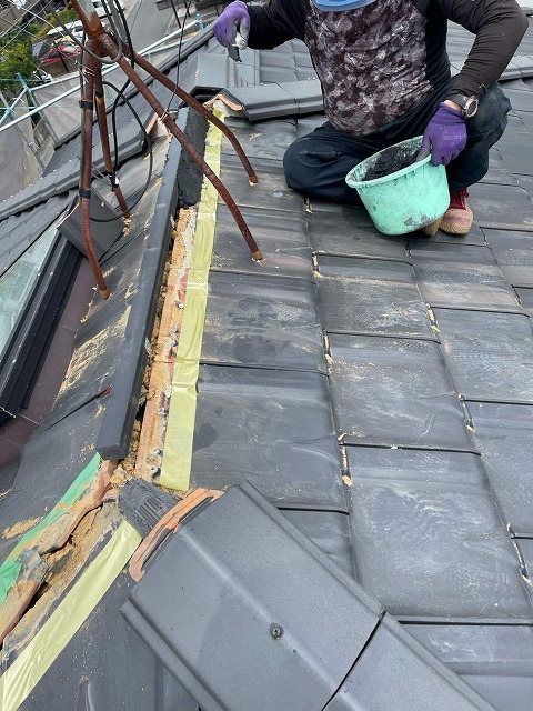 棟瓦取り直し工事の樹脂垂木に南蛮漆喰を詰めている屋根職人