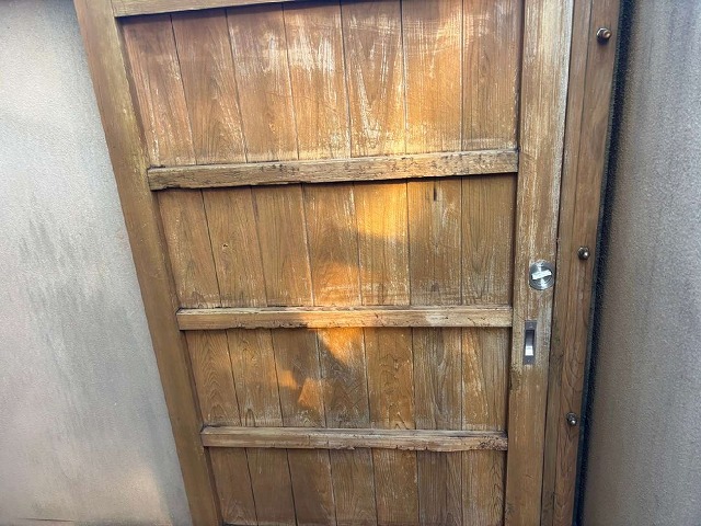 経年劣化により激しく色あせている和風住宅の木製ドア