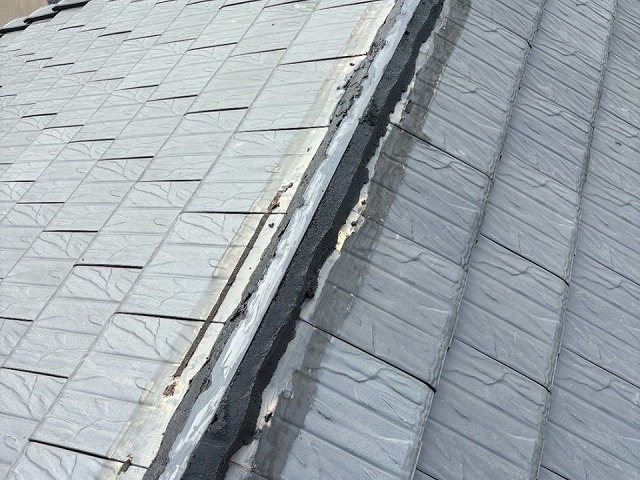 棟板金改修工事で漆喰材を塗り固めて棟瓦の土台を構築している様子