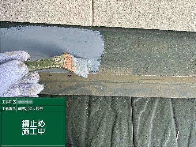 雨押え板金にハケでサビ止め塗料を下塗りしている施工の様子
