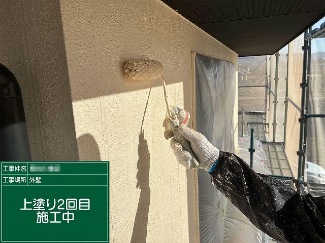 サイディング外壁へ上塗り（上塗り2回目）をローラーで施工している様子