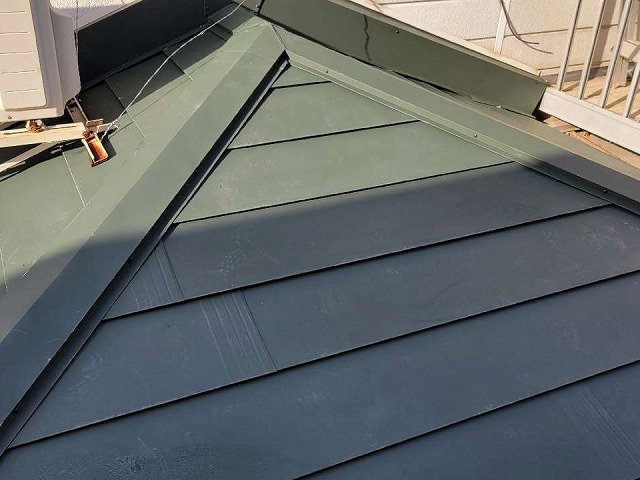 グリーン系の色のガルバリウム鋼板屋根で葺き替えが完了した住宅の下屋根
