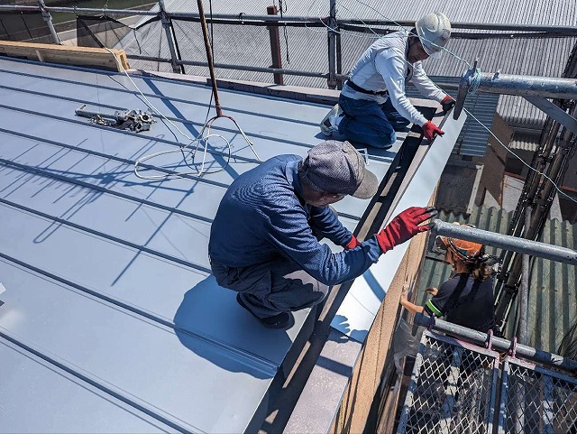 工場建物のパラペット部に笠木を取り付けている様子