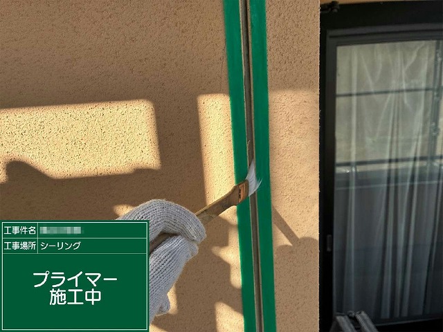マスキングテープで養生した目地内部に刷毛でプライマーを塗布している様子