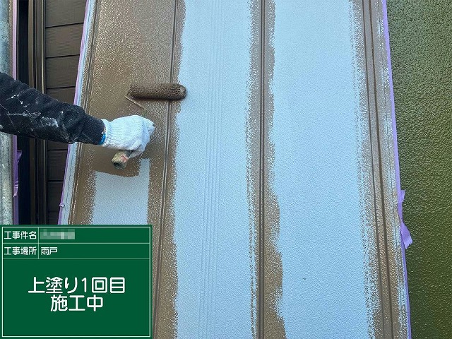 雨戸にローラーで上塗り1回目を塗り重ねている施工中の様子