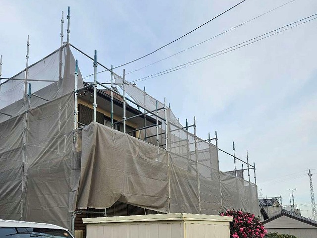 足場と養生シートで全体を覆われた住宅の外観