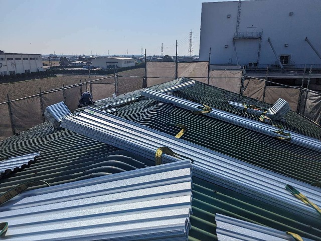 屋根の上にガルバリウム鋼板製の折板屋根を荷揚げしている状況