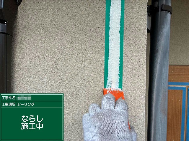 新しいコーキング材を目地に充填しヘラで空隙なく押さえながら表面を均している様子