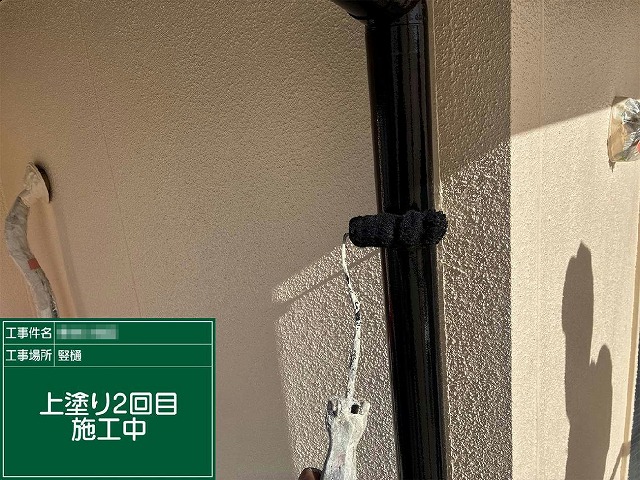 縦樋にローラーで上塗り2回目を施工している様子