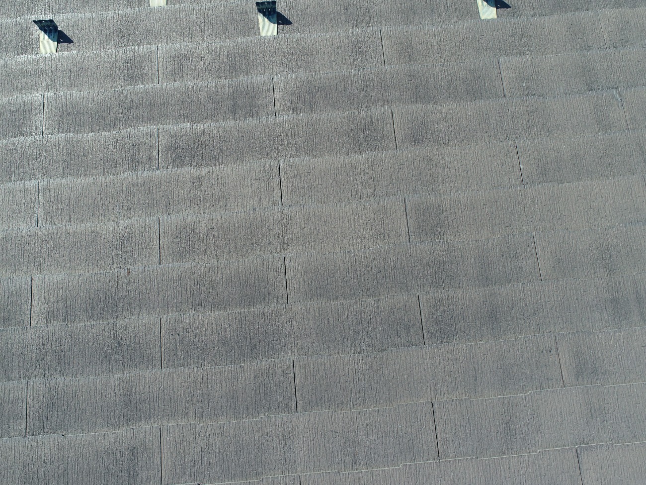 全体に色あせが進行している3階建て住宅のスレート屋根