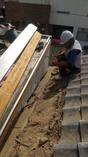 谷板金を撤去するために外壁板金瓦を取り除いている屋根職人