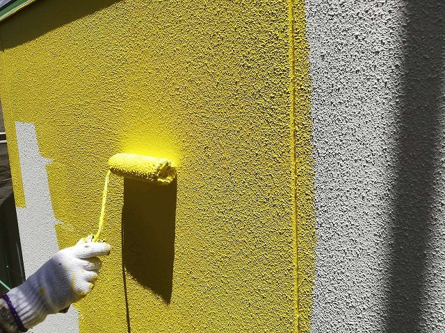 下塗りの上にローラーで外壁塗装を行う職人