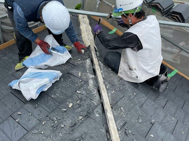 棟瓦の漆喰をはつって除去している屋根職人