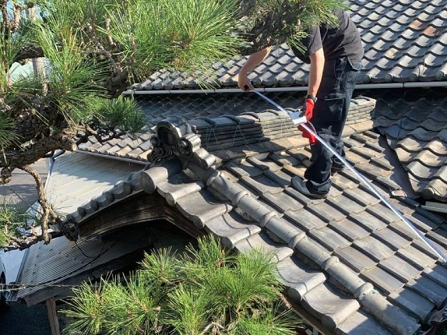 屋根棟部の漆喰の劣化を確認する点検員