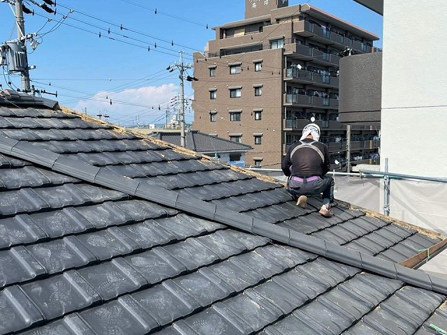 劣化で傷んだ棟瓦を取り除いている屋根職人